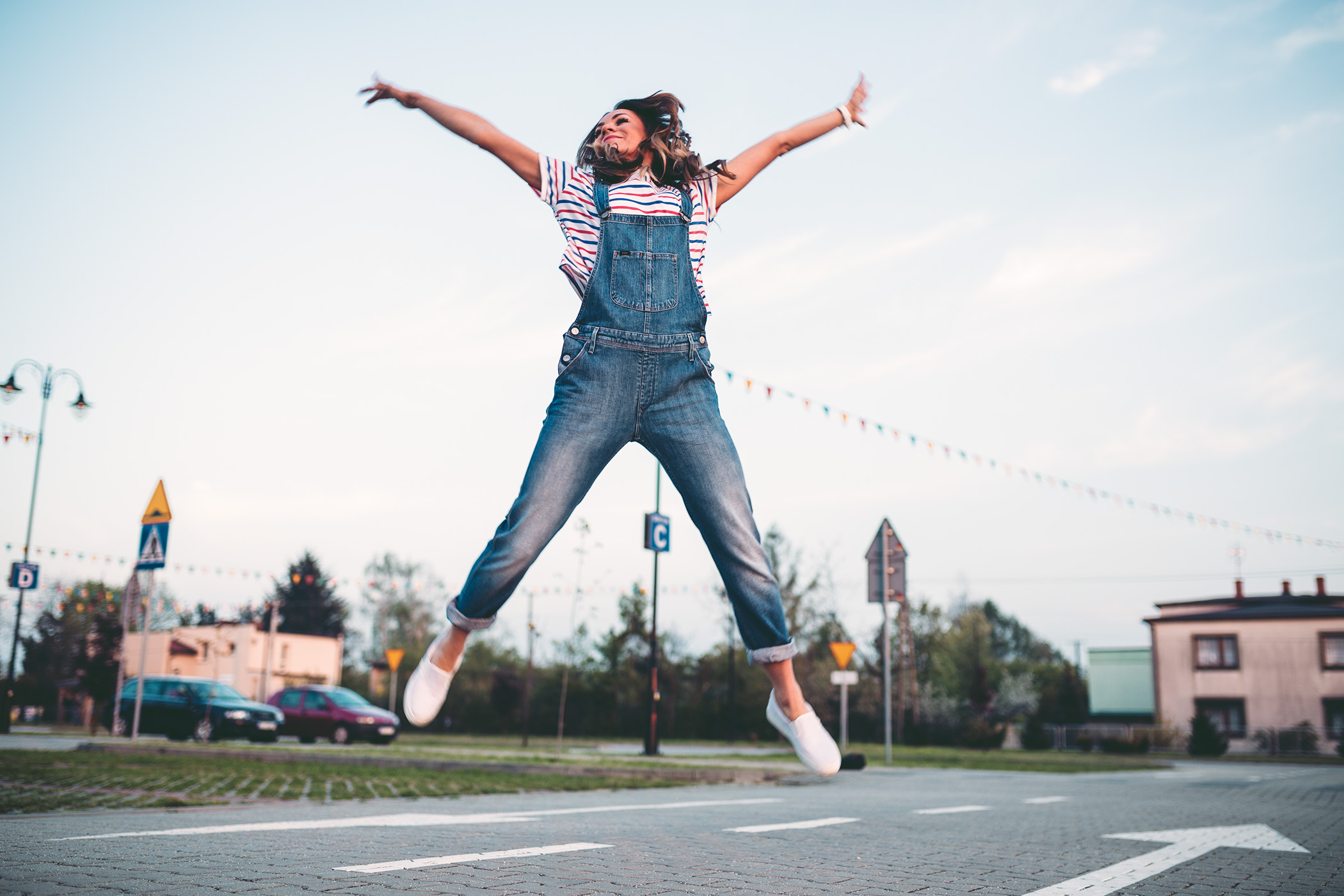 Skacząca kobieta ubrana w dżinsowe ogrodniczki